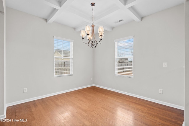 spare room with beamed ceiling, hardwood / wood-style flooring, and a wealth of natural light