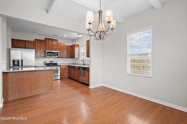 kitchen with beamed ceiling, stainless steel appliances, hanging light fixtures, and light hardwood / wood-style flooring