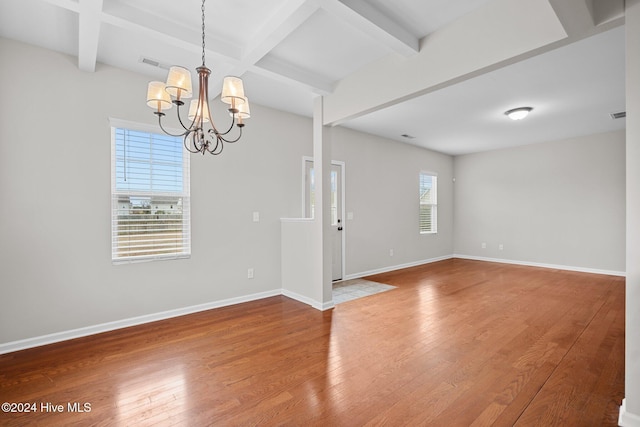 empty room featuring coffered ceiling, a notable chandelier, beam ceiling, and hardwood / wood-style flooring