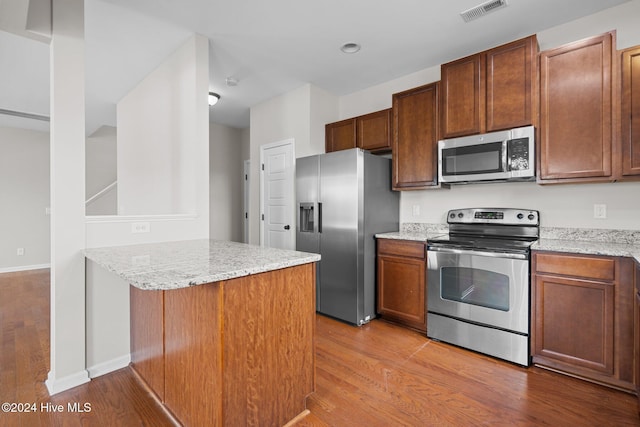 kitchen featuring appliances with stainless steel finishes, kitchen peninsula, light stone counters, and light hardwood / wood-style floors