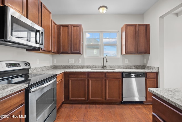 kitchen featuring sink, dark wood-type flooring, stainless steel appliances, and light stone countertops