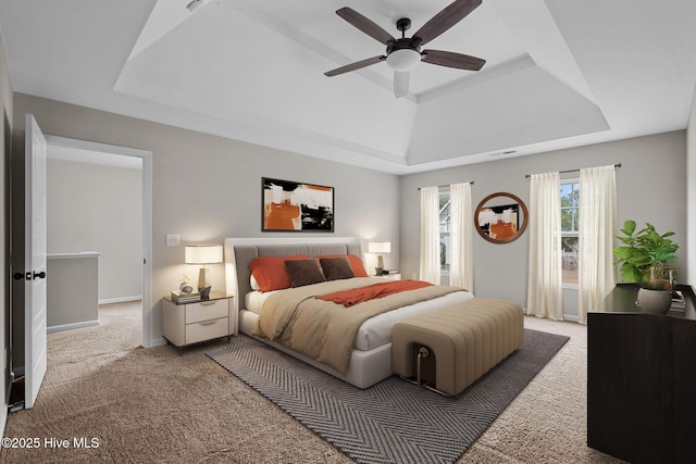 bedroom featuring a raised ceiling, carpet flooring, and ceiling fan