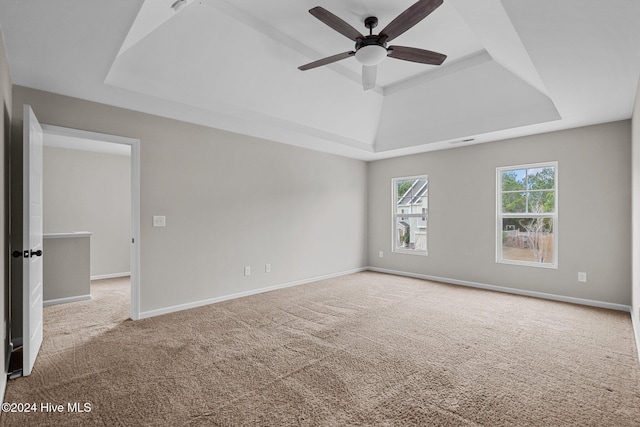 empty room with carpet floors, ceiling fan, and a tray ceiling