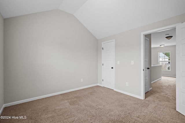 unfurnished bedroom featuring light colored carpet and lofted ceiling