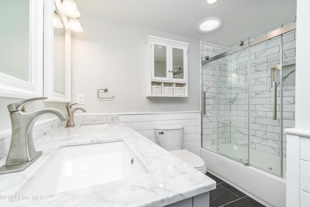 full bathroom with tile patterned flooring, vanity, bath / shower combo with glass door, and toilet