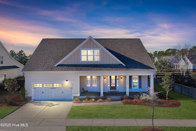 view of front of house with driveway, a lawn, an attached garage, covered porch, and fence