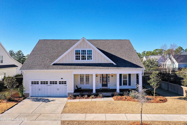 view of front of home with french doors, covered porch, concrete driveway, fence, and a garage