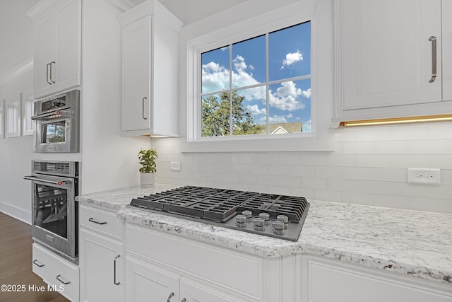 4450 Old Towne St, Wilmington, NC 28412 - kitchen featuring stainless steel gas stovetop, white cabinetry, dark wood-type flooring, decorative backsplash, and light stone counters