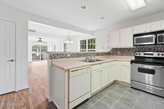 kitchen with kitchen peninsula, appliances with stainless steel finishes, a healthy amount of sunlight, and sink