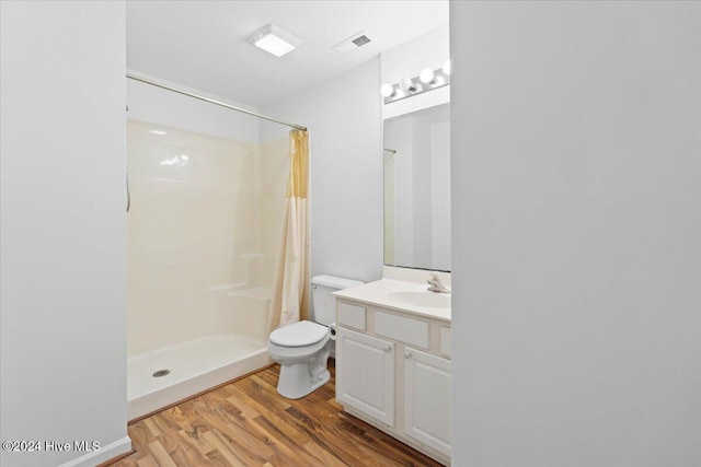 bathroom featuring walk in shower, vanity, wood-type flooring, and toilet