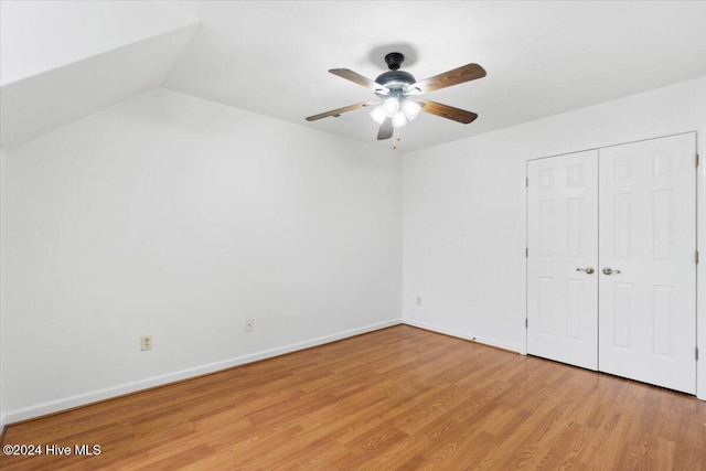 unfurnished bedroom with ceiling fan, a closet, vaulted ceiling, and light hardwood / wood-style flooring