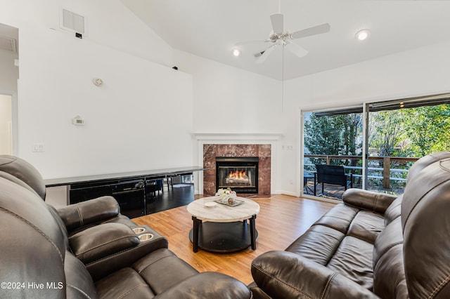 living room featuring a high end fireplace, hardwood / wood-style flooring, vaulted ceiling, and ceiling fan