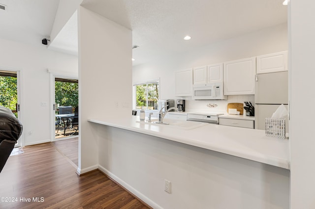 kitchen with dark hardwood / wood-style flooring, white appliances, sink, white cabinetry, and lofted ceiling