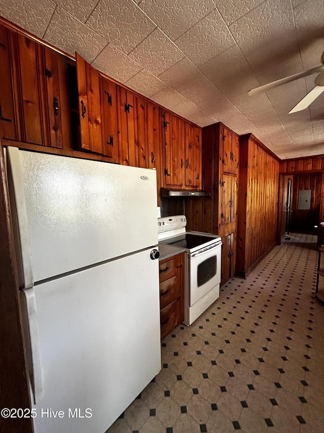 kitchen with white appliances, ceiling fan, and wooden walls