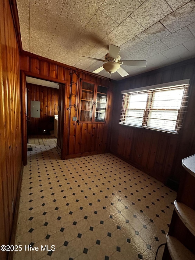 unfurnished room featuring electric panel, wood walls, and ceiling fan