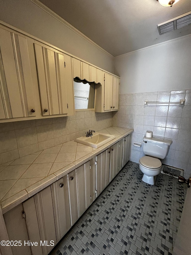 bathroom featuring vanity, ornamental molding, tile walls, and toilet