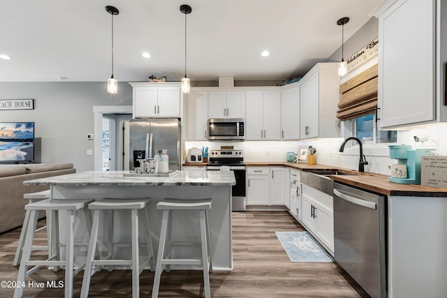 kitchen featuring white cabinets, pendant lighting, a center island, and stainless steel appliances