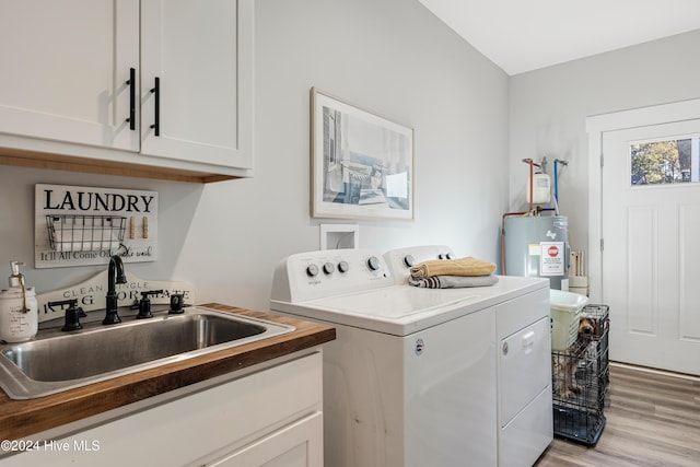 laundry room with cabinets, sink, separate washer and dryer, light wood-type flooring, and water heater