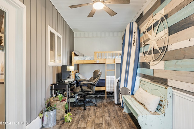 office area featuring dark hardwood / wood-style flooring, ceiling fan, and wood walls