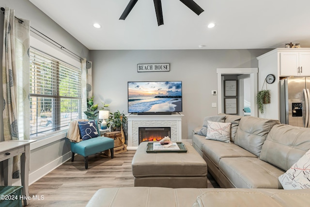 living room featuring ceiling fan, light hardwood / wood-style floors, and a fireplace