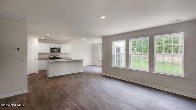 kitchen with light stone counters, dark hardwood / wood-style flooring, a center island with sink, white cabinets, and white stove