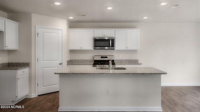 kitchen featuring white cabinets, appliances with stainless steel finishes, dark hardwood / wood-style flooring, and an island with sink