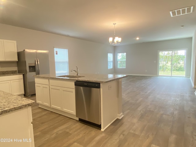 kitchen featuring a center island with sink, sink, hanging light fixtures, white cabinetry, and stainless steel appliances