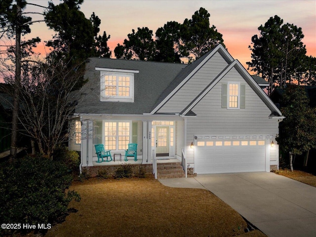 view of front of house with a garage, covered porch, and a lawn