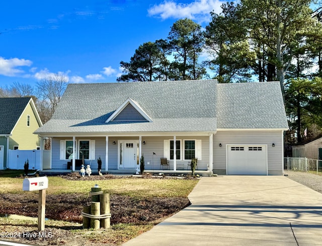 view of front of home with covered porch, a front yard, and a garage