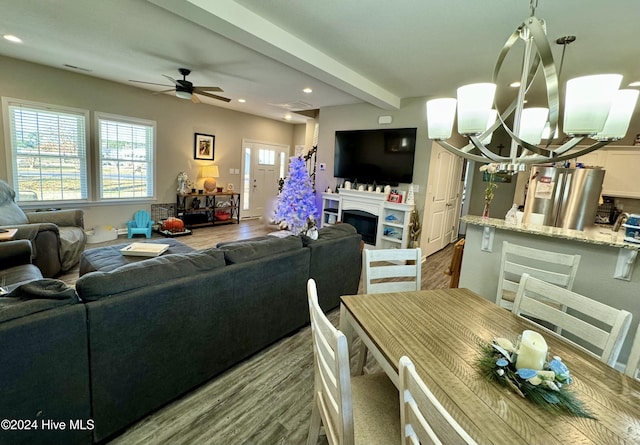 living room with beamed ceiling, ceiling fan with notable chandelier, and hardwood / wood-style flooring