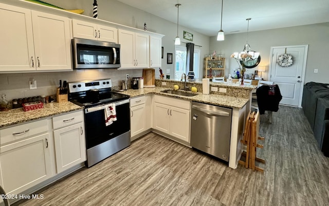 kitchen featuring sink, hanging light fixtures, kitchen peninsula, white cabinets, and appliances with stainless steel finishes