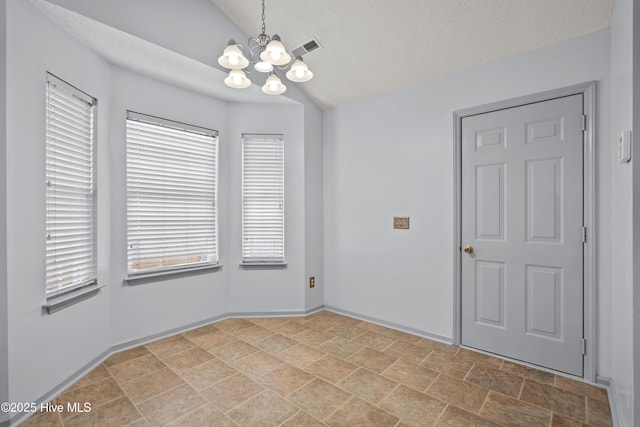 spare room with a textured ceiling, vaulted ceiling, and an inviting chandelier