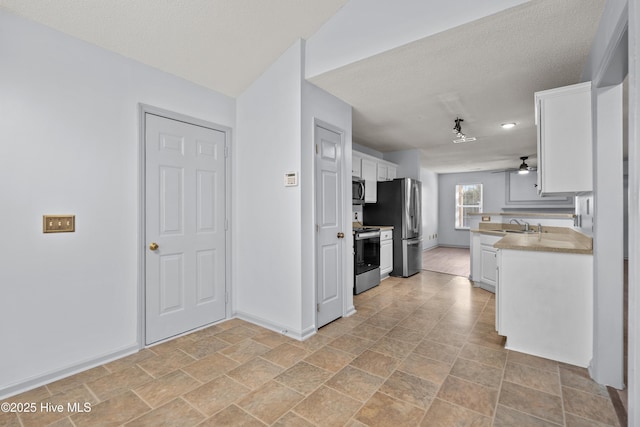 kitchen featuring a textured ceiling, stainless steel appliances, white cabinetry, and sink