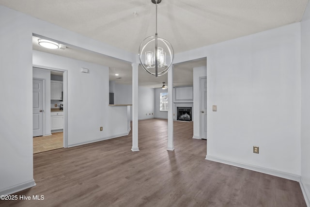 unfurnished dining area featuring hardwood / wood-style floors, ceiling fan with notable chandelier, and a textured ceiling