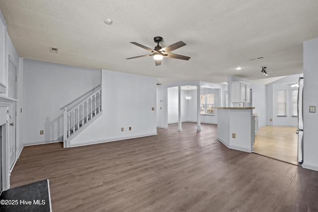 unfurnished living room with wood-type flooring, a textured ceiling, ceiling fan, and a healthy amount of sunlight