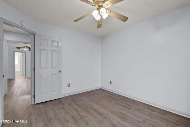 empty room with ceiling fan, light wood-type flooring, and a textured ceiling