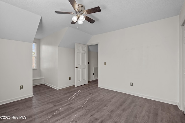 additional living space with ceiling fan, dark hardwood / wood-style floors, lofted ceiling, and a textured ceiling