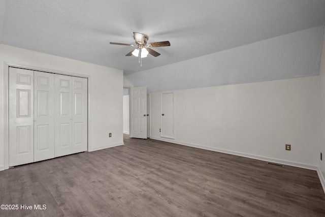 unfurnished bedroom with a textured ceiling, ceiling fan, wood-type flooring, a closet, and lofted ceiling