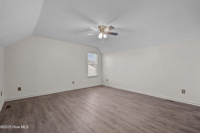 additional living space with a textured ceiling, ceiling fan, dark hardwood / wood-style floors, and vaulted ceiling