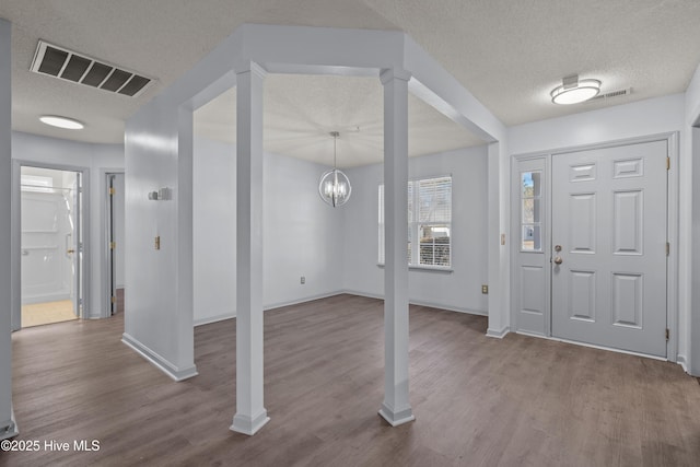 entryway featuring hardwood / wood-style floors, a textured ceiling, and an inviting chandelier