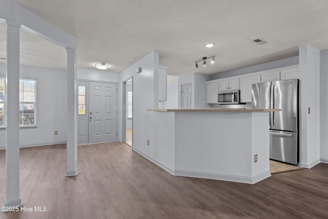 kitchen with kitchen peninsula, white cabinetry, stainless steel appliances, and light hardwood / wood-style flooring