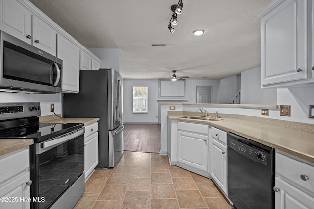 kitchen featuring rail lighting, sink, white cabinetry, and stainless steel appliances