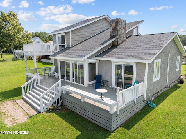 rear view of house with a sunroom, a deck, and a yard