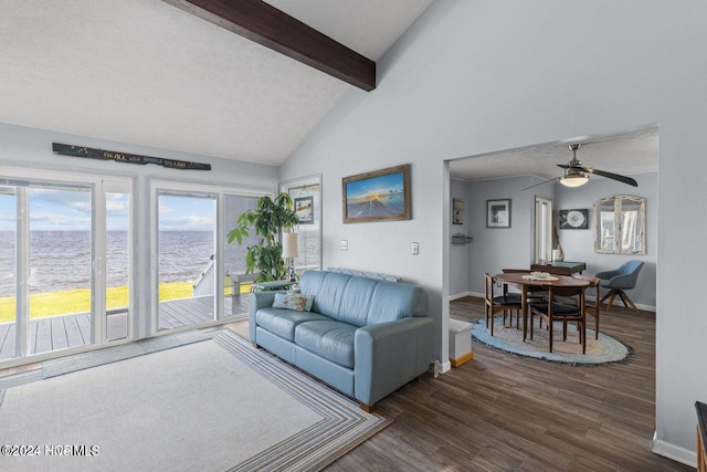 living room featuring lofted ceiling with beams, a water view, ceiling fan, a textured ceiling, and dark hardwood / wood-style flooring