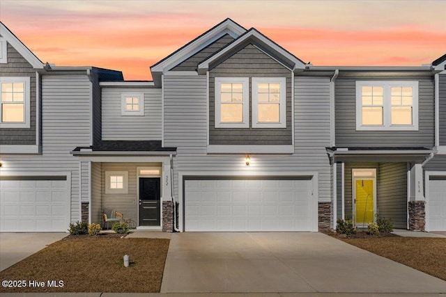 view of front of house featuring a garage, stone siding, and driveway