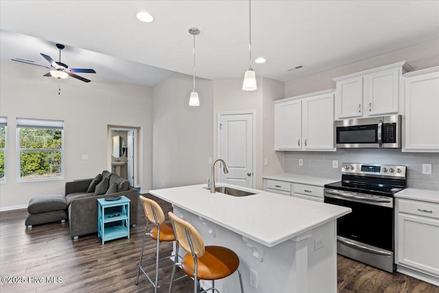 kitchen with white cabinets, decorative backsplash, stainless steel appliances, and an island with sink