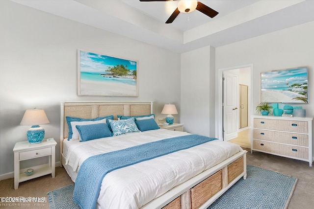 bedroom with carpet flooring, ceiling fan, and a tray ceiling