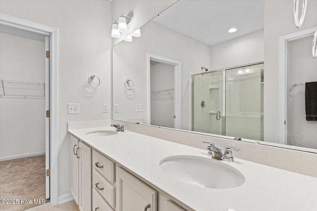 bathroom featuring a shower with door and vanity