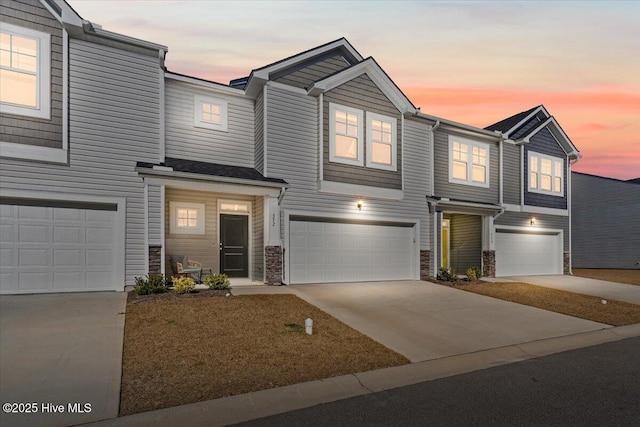 view of front of home featuring a garage, driveway, and stone siding