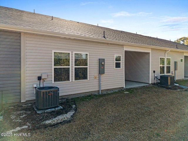 rear view of property featuring a lawn and central air condition unit